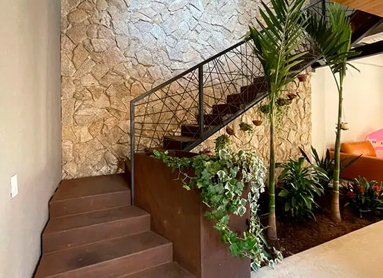 Escada de aço com jardim interno e parede de pedra