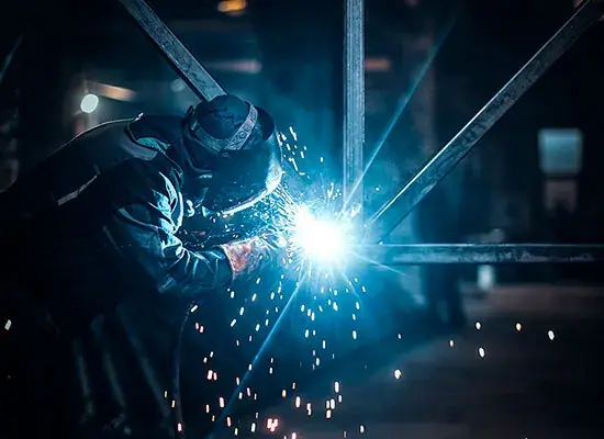 Soldador trabalhando, faíscas azuis na oficina